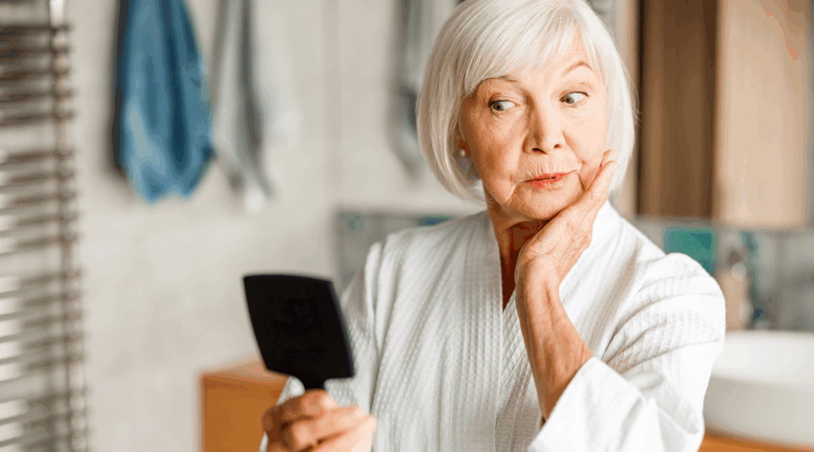 old woman looking at a small mirror she is holding